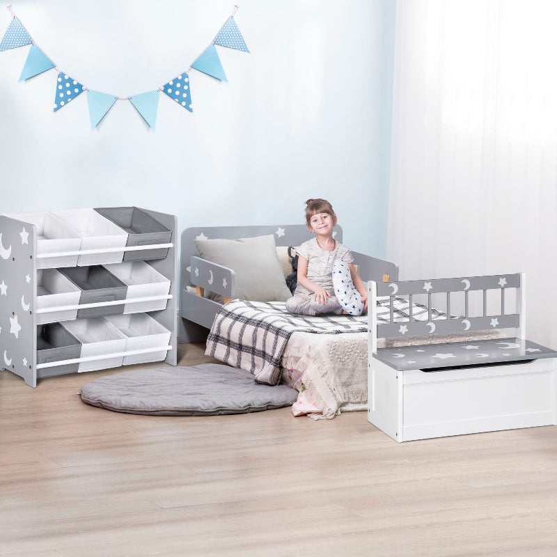 Child sitting on a bed in a room with gray and white furniture and decorative flags.