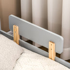 Gray bed rail with wooden supports on a bed against a curtain background