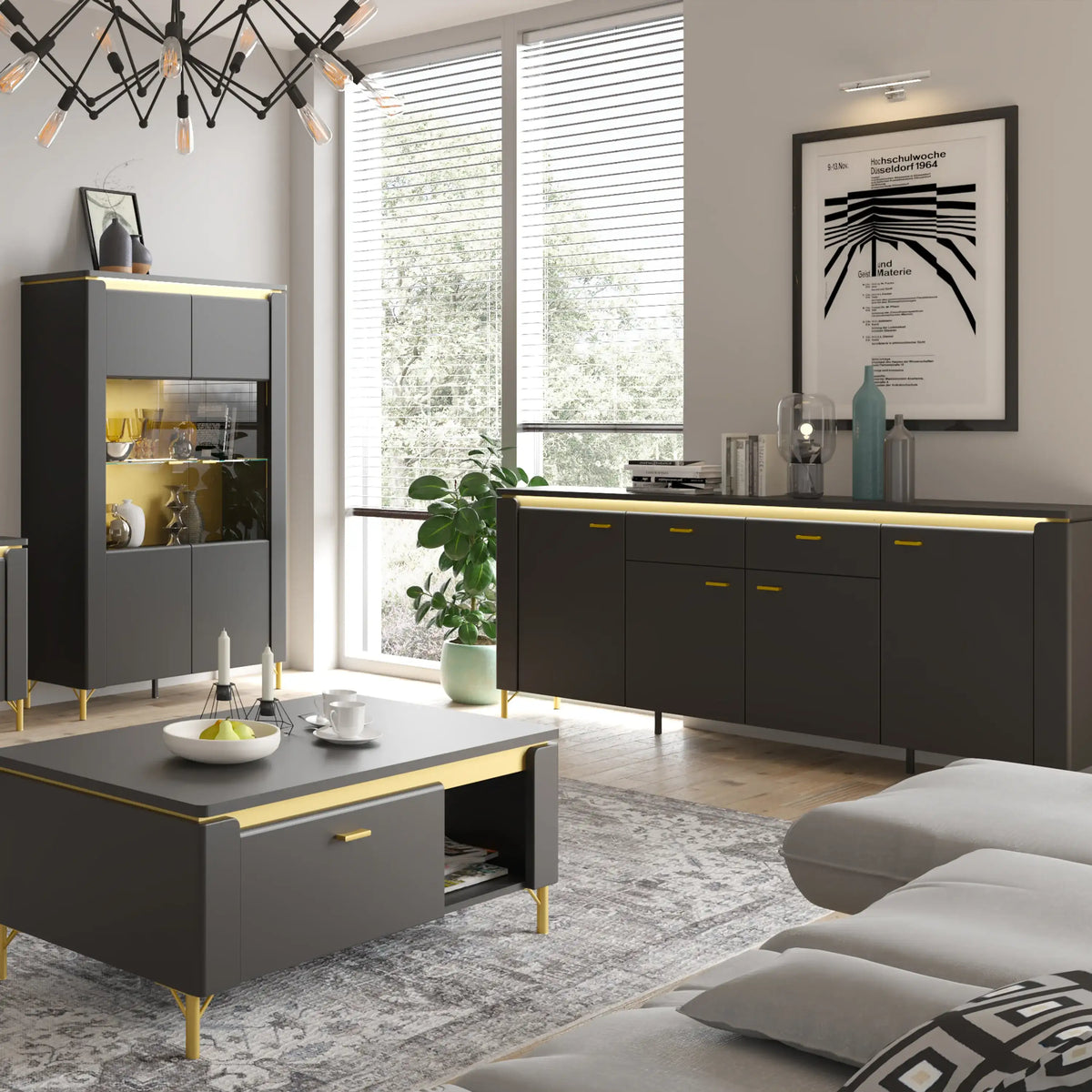 A modern living room furniture set featuring a dark gray coffee table with gold legs, a matching sideboard cabinet, a tall display cabinet, and a gray sofa in a bright, contemporary room.
