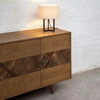A mid-century modern wooden sideboard with six drawers, featuring a herringbone wood inlay pattern across the center. 