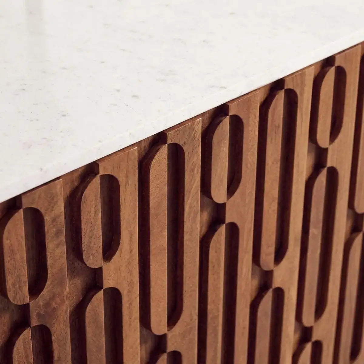 Close-up of a modern wooden cabinet with a white marble countertop, featuring a carved geometric pattern of interlocking vertical ovals.