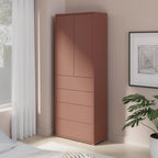 Tall pink wardrobe in a bedroom with a plant and framed picture on the wall.