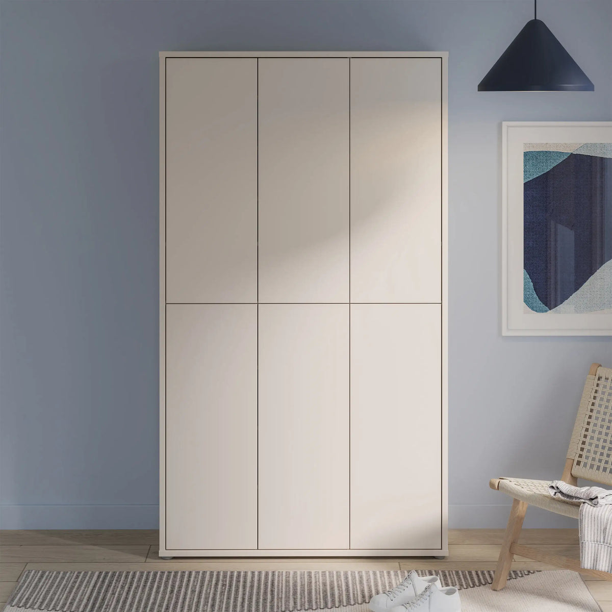 Beige wardrobe against a blue wall with a chair and abstract art in the background