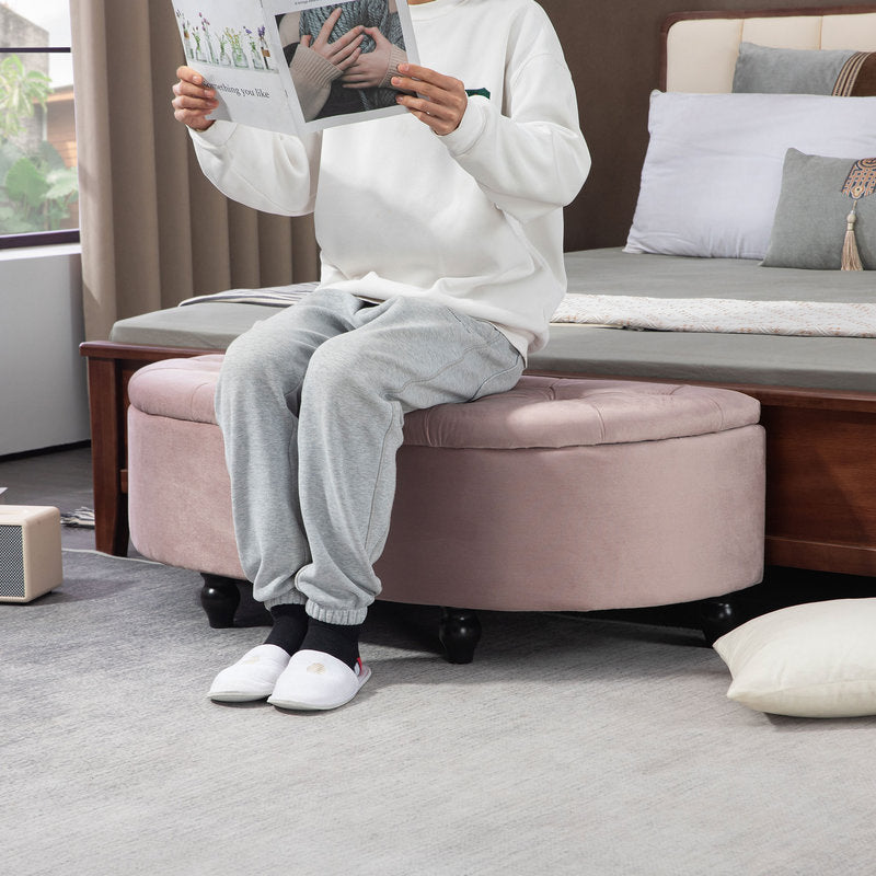 Person sitting on a round pink ottoman reading a newspaper in a living room.