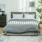 Gray bed with plaid blanket in a bedroom setting
