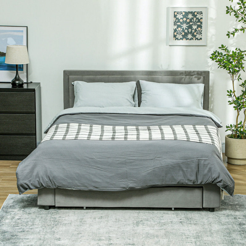 Gray bed with plaid blanket in a bedroom setting