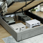 Gray bed with storage drawers open, revealing various boxes and a suitcase.