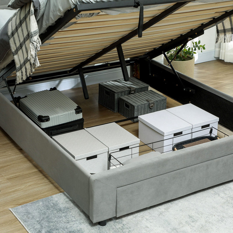 Gray bed with storage drawers open, revealing various boxes and a suitcase.