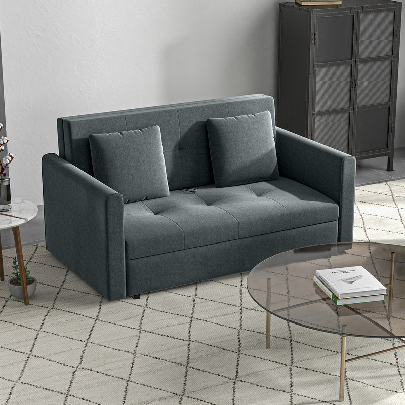 Gray sofa bed in a modern living room setting with a glass coffee table and metal cabinet.