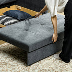 Person adjusting a gray upholstered bench with pillows on a patterned rug.