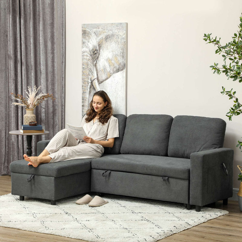 Woman sitting on a gray sectional sofa in a living room with a large abstract painting on the wall.