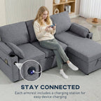 Woman sitting on a gray sectional sofa with charging station feature, in a living room setting.