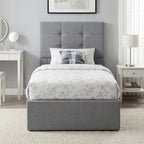 Gray upholstered bed with floral bedding in a bedroom setting.