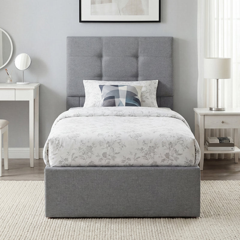 Gray upholstered bed with floral bedding in a bedroom setting.