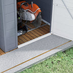 Lawn mower inside a storage shed with a concrete path leading to it.