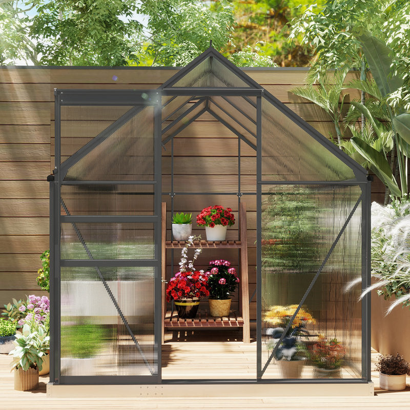 Small greenhouse with plants inside, surrounded by greenery