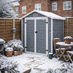 Gray garden shed with snow on the roof in a backyard setting
