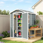 Grey garden shed with open doors, containing gardening tools and supplies, on a wooden platform with a clear sky background.