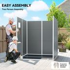 Two people assembling a gray outdoor privacy screen with tools and protective gloves on a wooden deck.