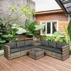Outdoor patio furniture set with gray cushions on a wooden deck, surrounded by plants.