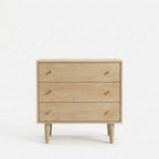 A three-drawer wooden chest of drawers with a light oak finish and small tapered legs, shown against a plain white background.